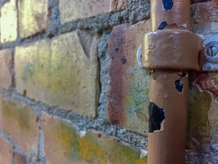 Partial view of a broken water pipe against a brick wallの写真素材
