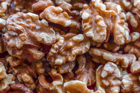 Overhead close up view of a bunch of walnuts without their shells on a red underlayの写真素材