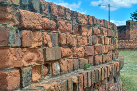 A low red brick wall curves away towards another brick wall in the backgroundの写真素材