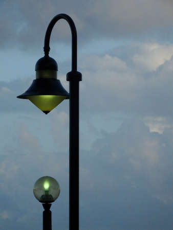 Two lampposts aligned against a cloudy blue skyの写真素材