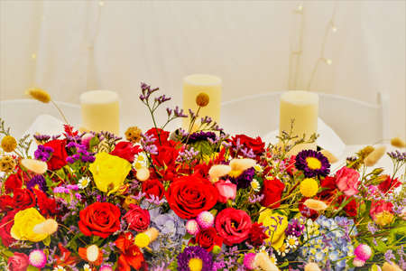Candles and colorful floral arrangement against a white backgroundの写真素材