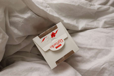 Nice gift for a girl. Raffaello's box of chocolates stands in a white bed view from the top. 12.03.2021, Russia, Altai region, Barnaulのeditorial素材