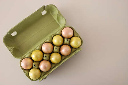Green container for Easter eggs of green and pink color in a checkerboard pattern on a white...