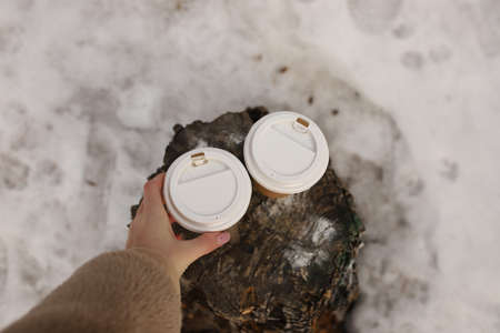 The girl's hand takes coffee from a hemp, during a winter walk through the forest. First-person...