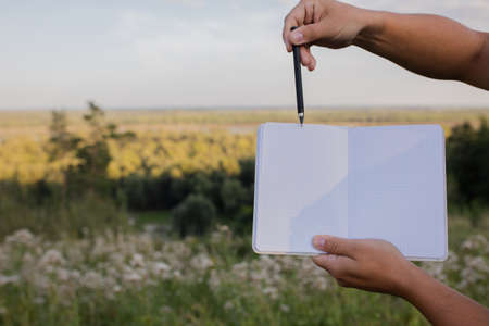 The man shows a pen in a notebook, with a place for an inscription, text. Outdoor training. selectiv focusの写真素材