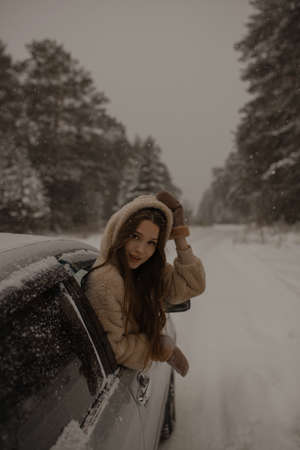 A young girl leaned up to her waist from the open window of the car. A young girl leaned out of the...