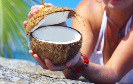 View of a woman opening big coconut in tropical environmentの写真素材