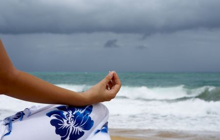 View of womans hand during yoga meditation on stormy beachの写真素材