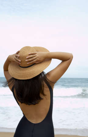 view of  nice woman in black swimming wear holding her straw hat
