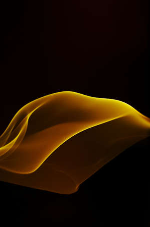 view of gold smooth smoke curling through the blacknessの写真素材