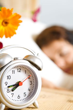 Close up view of  table clock and woman sleeping on backの写真素材