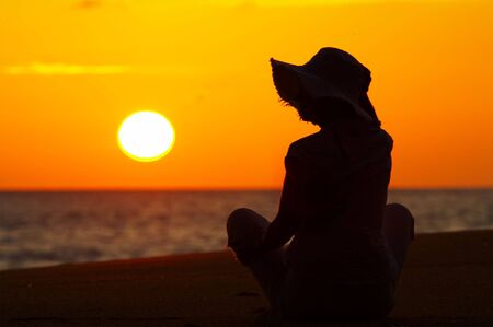 silhouette of a woman on the beach during sunsetの写真素材