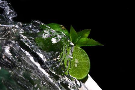 Close up view of limes getting splashed by water on black backの写真素材