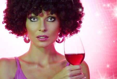 Portrait of young nice woman with glass of wine on pink backの写真素材