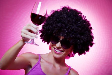 Portrait of young nice woman with glass of wine on pink backの写真素材