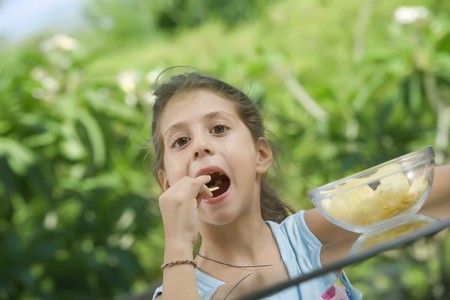 portrait of nice little girl eating chips  in summer environmentの写真素材