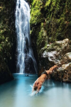 portrait of young man diving  in tropical waterfallの写真素材