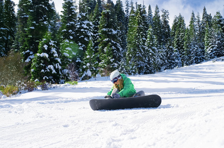 view of a young girl snowboarding in winter environmentの写真素材