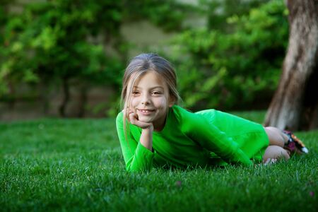 portrait of little girl laying on the grass in summer environmentの写真素材