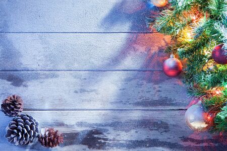 view  of lit Christmas tree  and cones on snowbound  wooden back