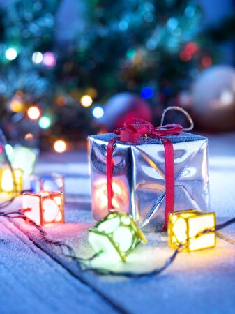 close up view  of lights and gift box on snowbound  wooden backの写真素材