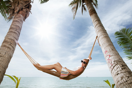 view of nice young lady swinging  in hummock on tropical beachの写真素材