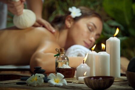 portrait of young beautiful woman in spa environment. focused on candles.の写真素材