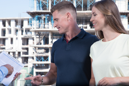 portrait of nice young couple studying contract on construction area backgroundの写真素材