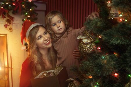 portrait of beautiful little girl with her mama in christmas environment