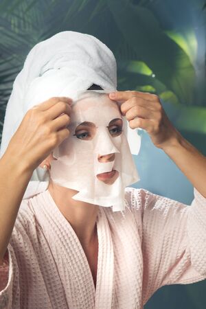 close up portrait of nice young woman applying facial maskの写真素材