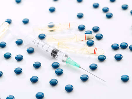 Close up view of the ampule with medicine, pills and syringe on white back