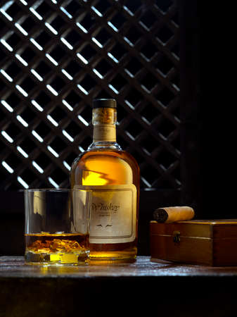 NO LOGOS OR TRADEMARKS!  SELF MADE LABELS! close up view of cigar, bottle of whiskey and glass aside ongrey back.の写真素材