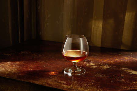 view of glass of  cognac on brown color wooden table surface