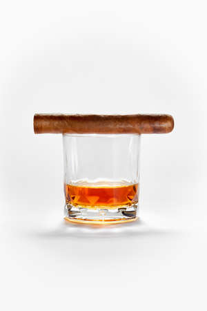 Closed up view of glass of whiskey with cigar on top on white backの写真素材