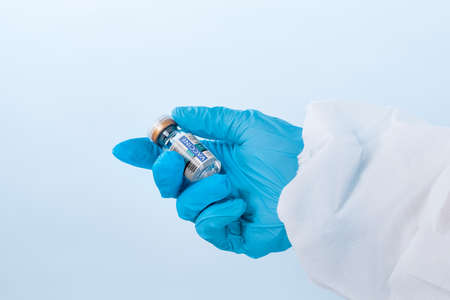 NO LOGOS OR TRADEMARKS!  SELF MADE LABELS! Close up view of doctorâs hand with an ampule of covid vaccine on blue backの写真素材