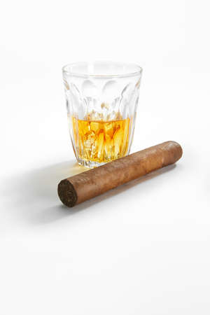 Closed up view of glass of whiskey with cigar on white back