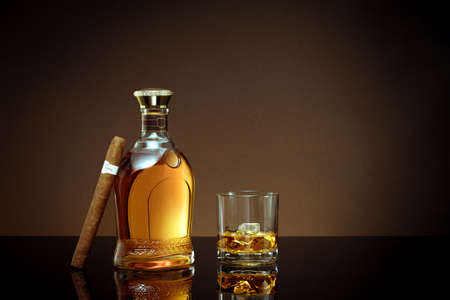 close up view of cigar, bottle of cognac and a glass aside on color back.の写真素材