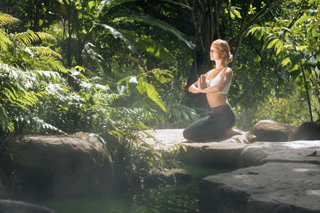 Portrait of young woman practicing yoga in tropic environmentの写真素材