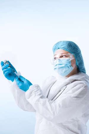 NO OR TRADEMARKS!  SELF MADE LABELS! Close up view of doctor with an ampule of vaccine and syringe on blue backの写真素材