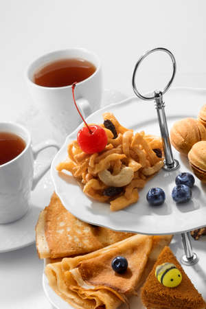 Close up view of dessert plate, china teapot and cups on white backgroundの写真素材
