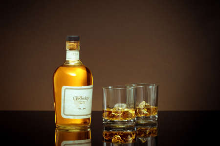 close up view of bottle of whiskey and a glasses aside on color back.の写真素材