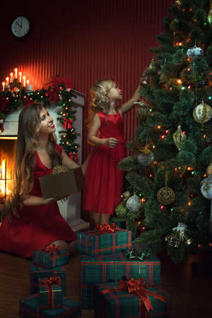 portrait of beautiful little girl with her mama in christmas environmentの写真素材