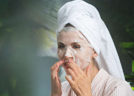 close up portrait of nice young woman applying facial maskの写真素材