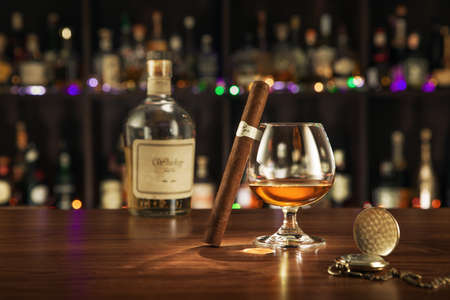 NO LOGOS OR TRADEMARKS!  SELF MADE LABELS!  close up view of cigar, bottle of cognac and a glass aside on color back.の写真素材