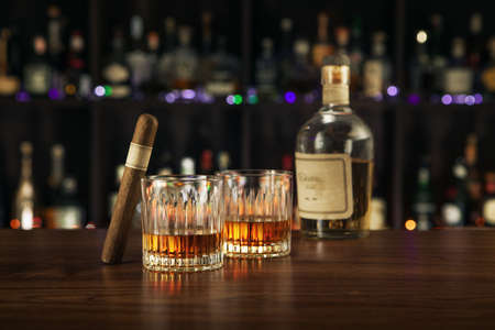 NO LOGOS OR TRADEMARKS!  SELF MADE LABELS! close up view of cigar, bottle of whiskey and atwo glasses aside on color back.の写真素材