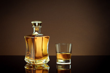 close up view of bottle of brandy and glass aside on color back.の写真素材