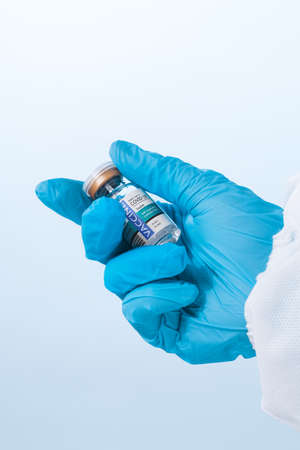 NO LOGOS OR TRADEMARKS!  SELF MADE LABELS! Close up view of doctorâs hand with an ampule of covid vaccine on blue backの写真素材
