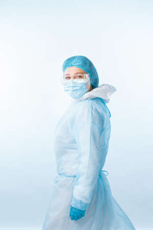 Portrait of doctor wearing protecting suit, gloves and mask on blue backの写真素材