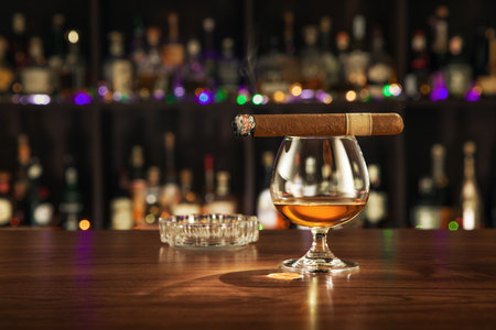 close up view of cigar and glass of cognac on color back.の写真素材