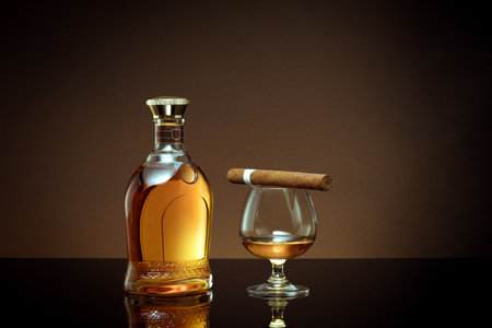 close up view of cigars, bottle of whiskey and glass aside on color back.の写真素材